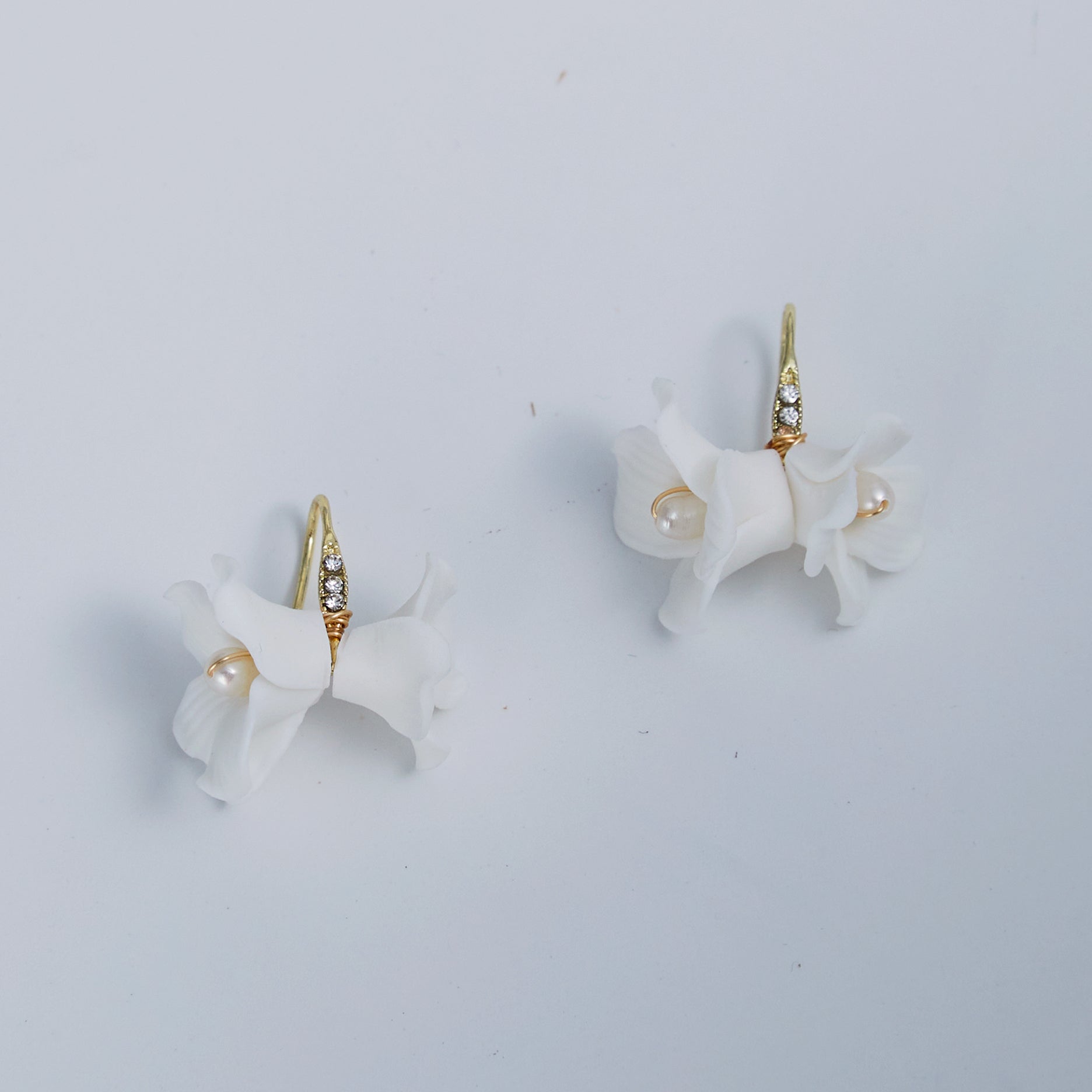 these flower bridal earrings  feature two delicate white clay flowers adorned with freshwater pearls and crystal-embellished French hooks that create a brilliant sparkle with every move.
