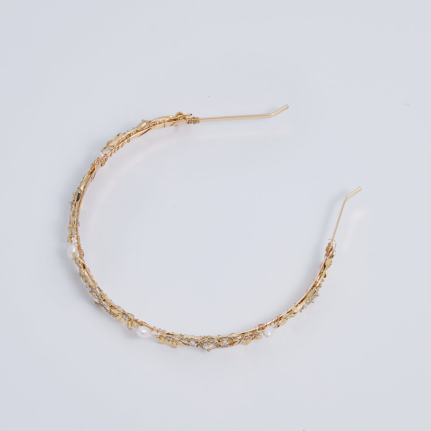 This slimline, modern gold headband is made from the most beautiful freshwater pearls and shimmering rhinestones. The minimalist floral design and timeless luxury of pearls and stones are always in style.