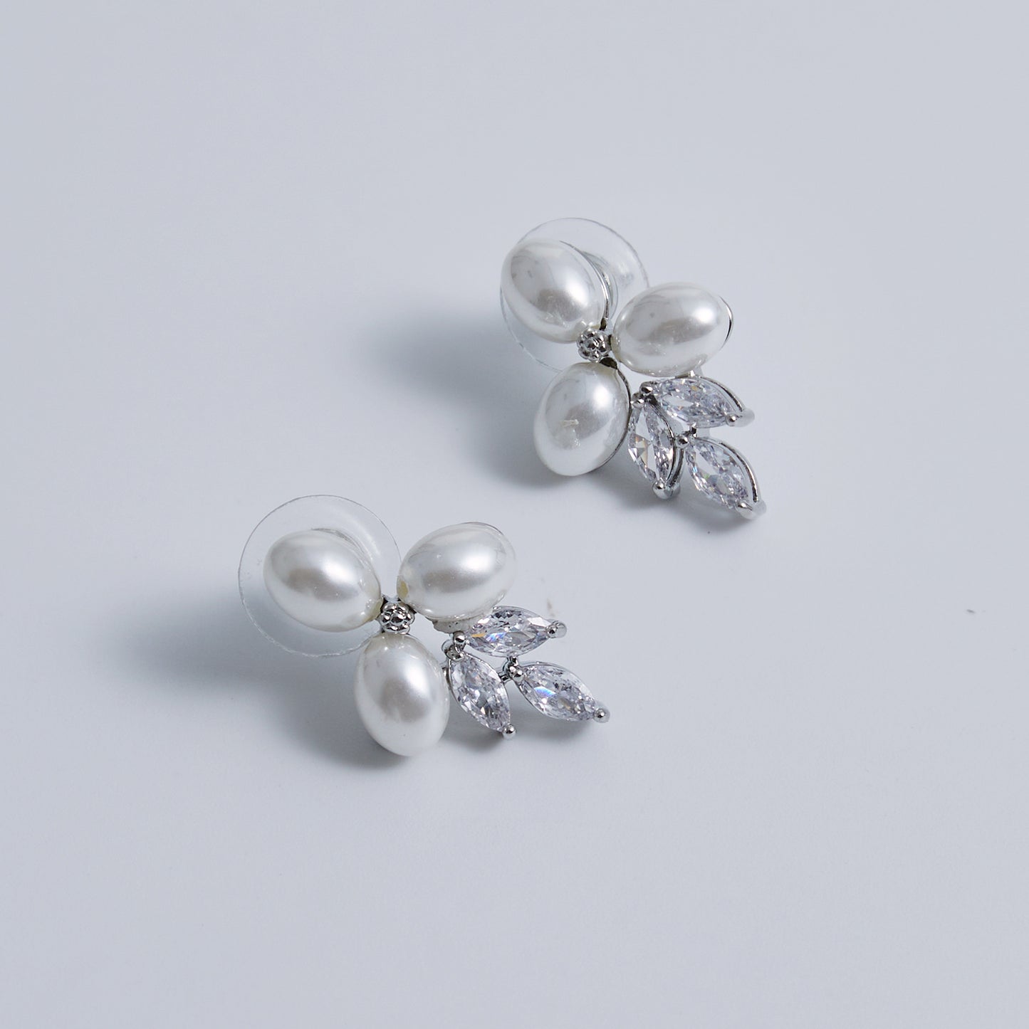 These stunning earrings feature leaf-like zirconia crystals that shimmer beneath three delicate pearls, evoking the graceful beauty of blooming flowers.