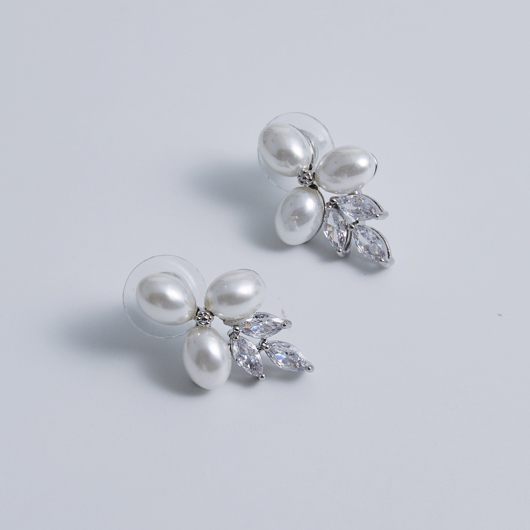These stunning earrings feature leaf-like zirconia crystals that shimmer beneath three delicate pearls, evoking the graceful beauty of blooming flowers.