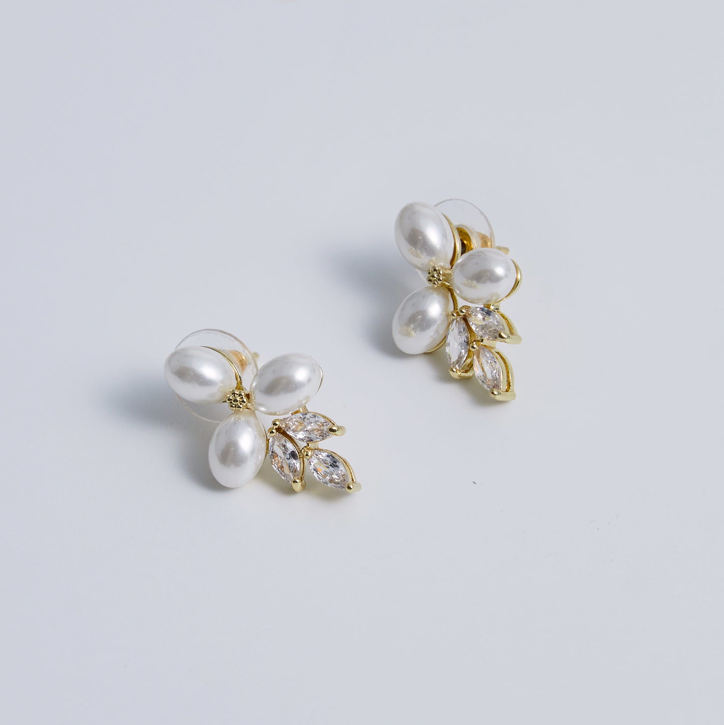 These stunning earrings feature leaf-like zirconia crystals that shimmer beneath three delicate pearls, evoking the graceful beauty of blooming flowers.