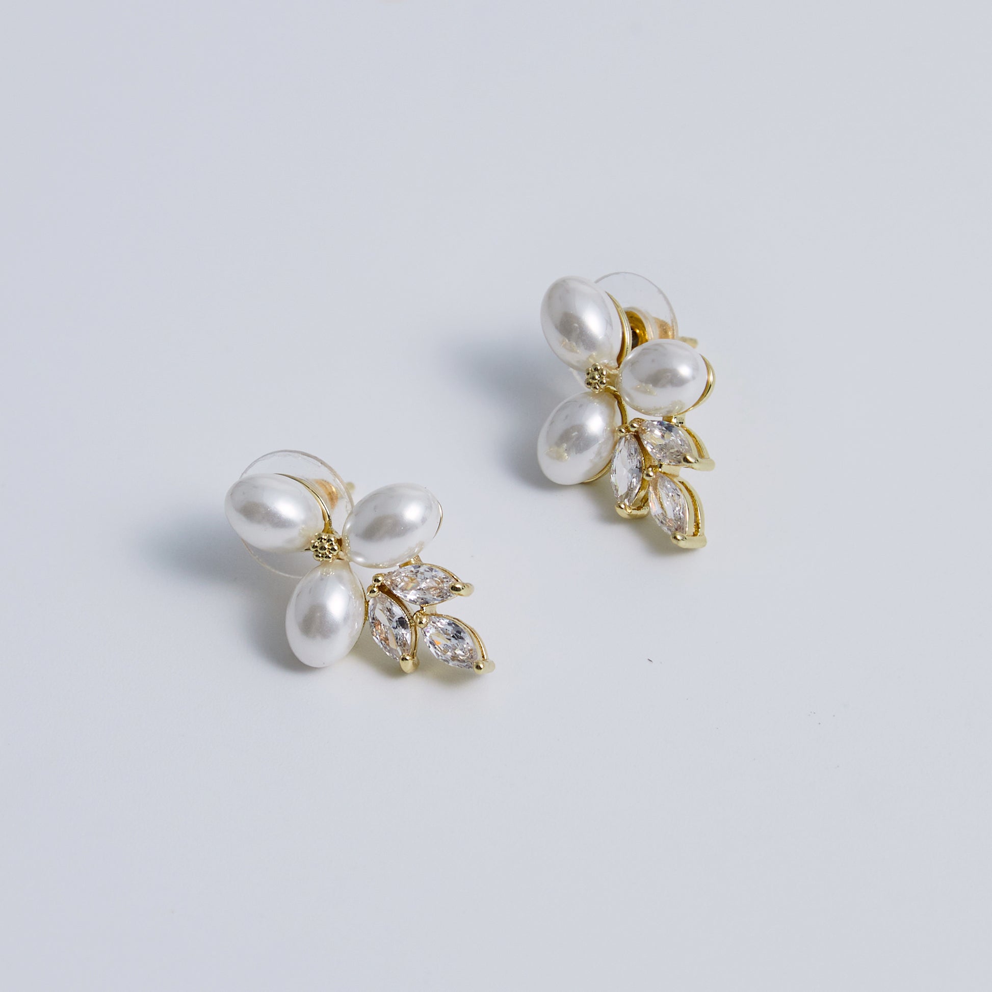 These stunning earrings feature leaf-like zirconia crystals that shimmer beneath three delicate pearls, evoking the graceful beauty of blooming flowers.