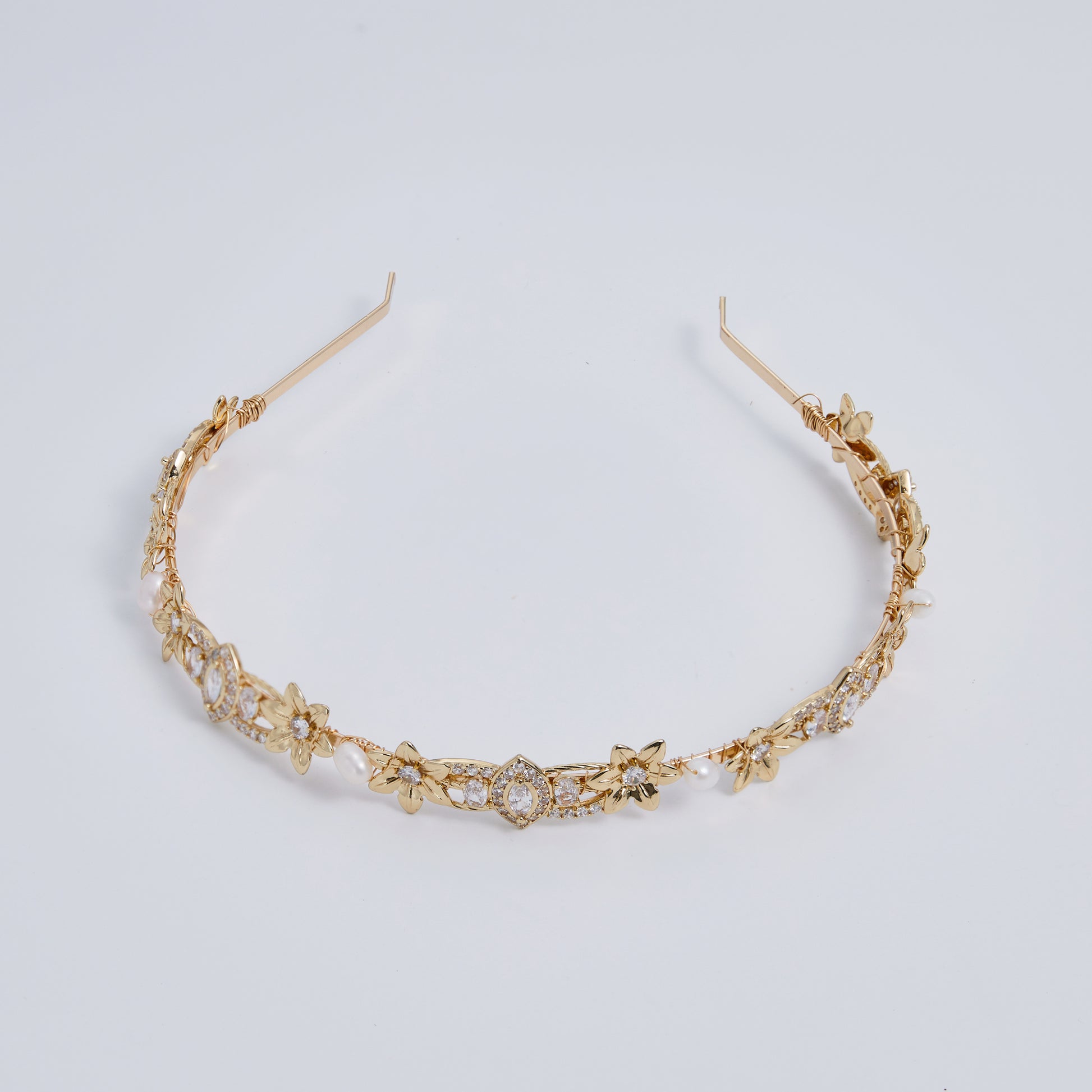 This slimline, modern gold headband is made from the most beautiful freshwater pearls and shimmering rhinestones. The minimalist floral design and timeless luxury of pearls and stones are always in style.