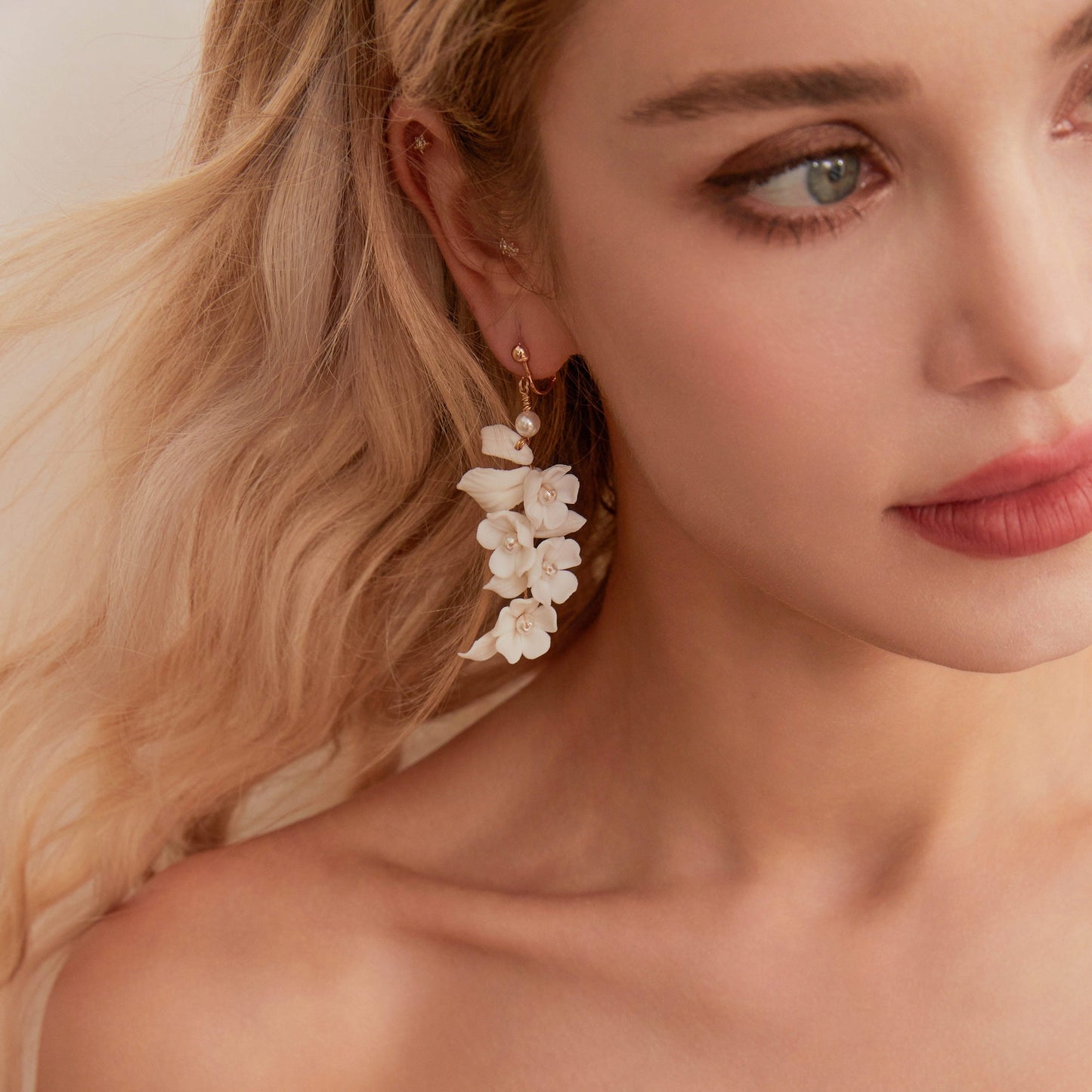 Carefully crafted by hand, these flower bridal earrings are a perfect match to our porcelain headpieces. Each earring features delicate white clay flowers and leaves adorned with shimmering freshwater pearls. These earrings have a long drop design that is sure to catch attention and make a statement.