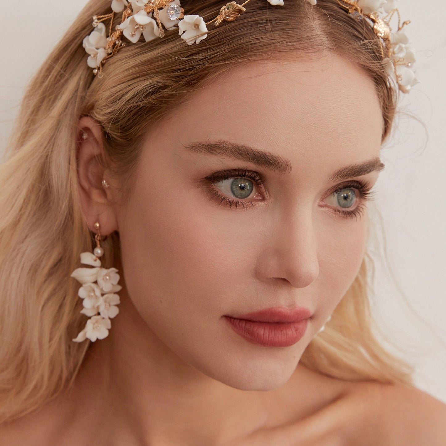 Carefully crafted by hand, these flower bridal earrings are a perfect match to our porcelain headpieces. Each earring features delicate white clay flowers and leaves adorned with shimmering freshwater pearls. These earrings have a long drop design that is sure to catch attention and make a statement.