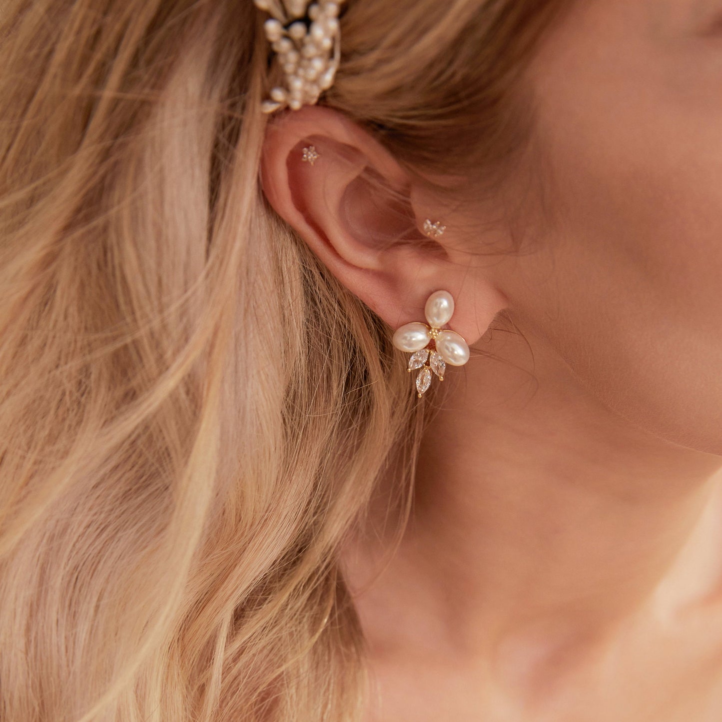 These stunning earrings feature leaf-like zirconia crystals that shimmer beneath three delicate pearls, evoking the graceful beauty of blooming flowers.