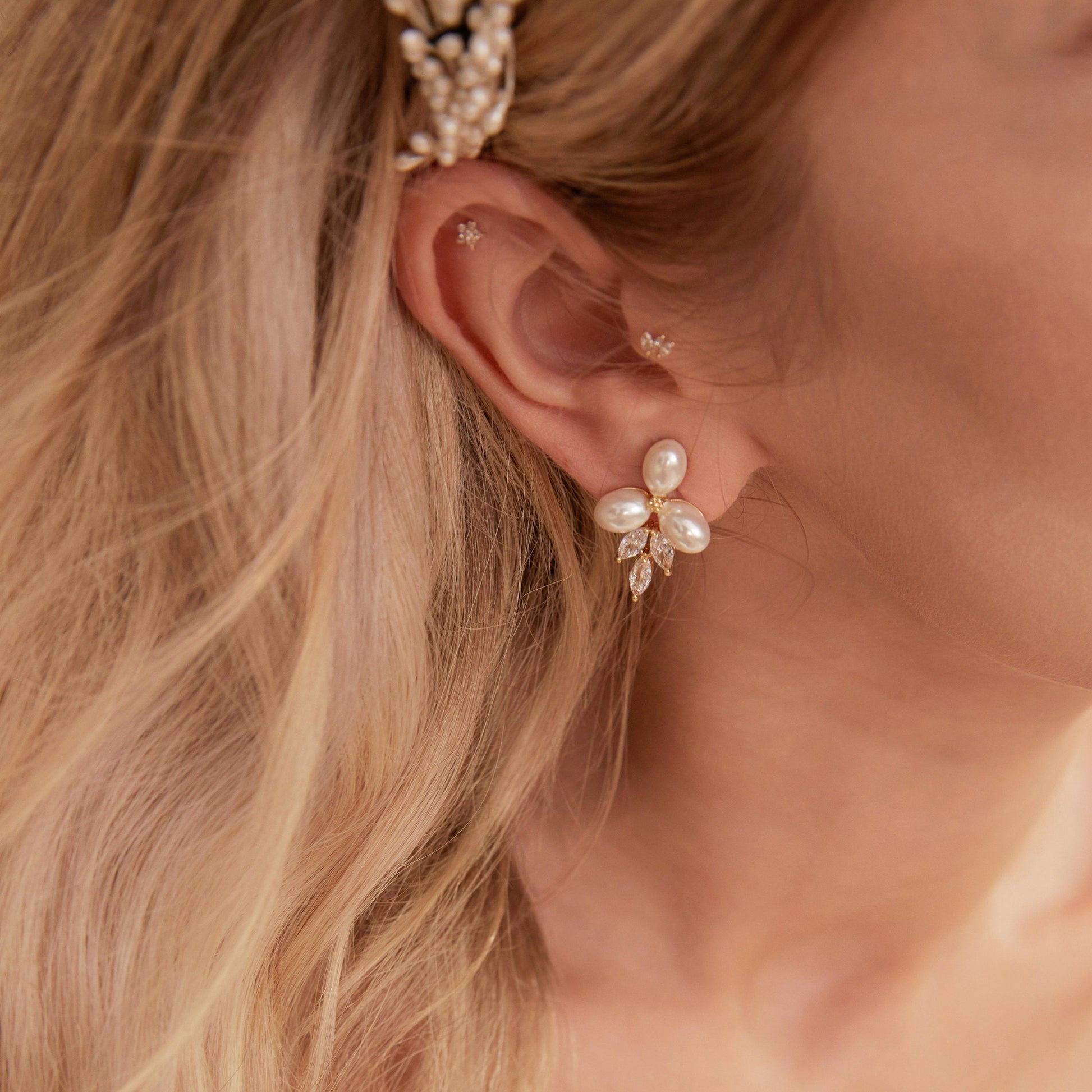These stunning earrings feature leaf-like zirconia crystals that shimmer beneath three delicate pearls, evoking the graceful beauty of blooming flowers.