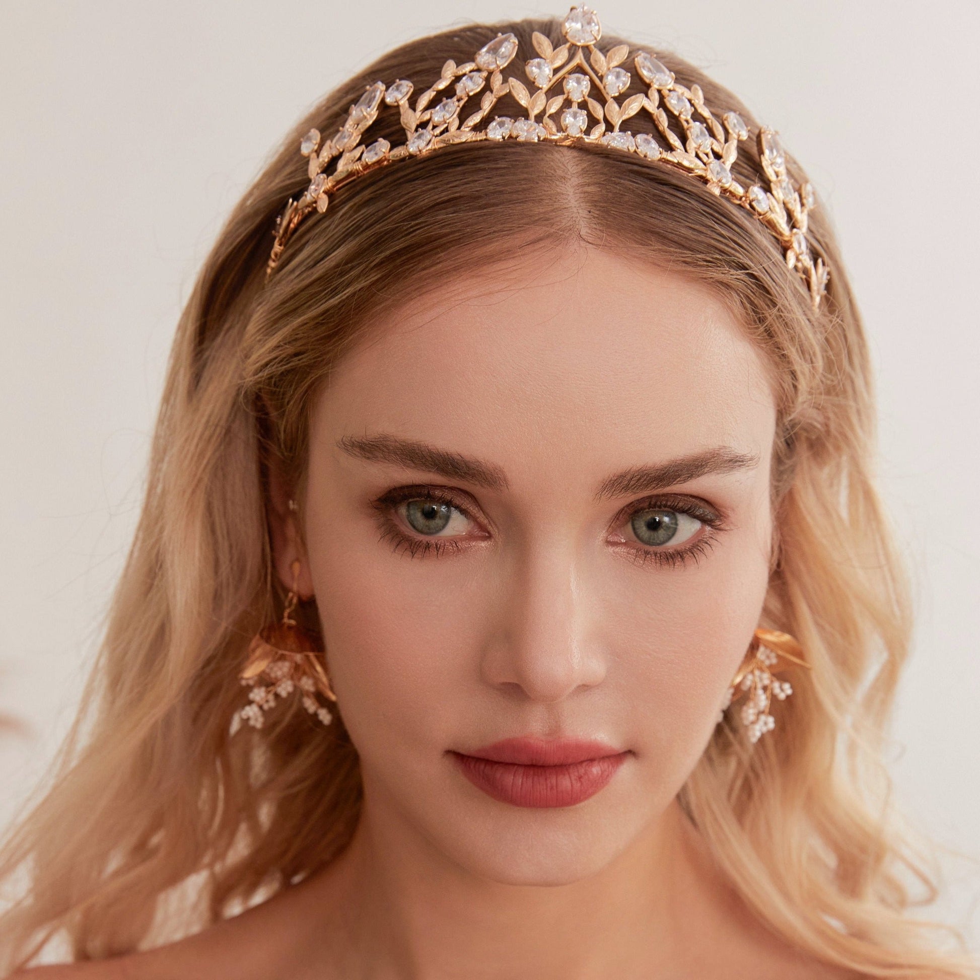 Victoria | Gold Crystal Bridal Crown Tiara - Handcrafted with attention to detail, this unique crown features delicate gold metal leaves intricately arranged alongside an array of dazzling rhinestone flowers in various sizes. The combination of gold and crystals creates a vintage-inspired woodland feel.