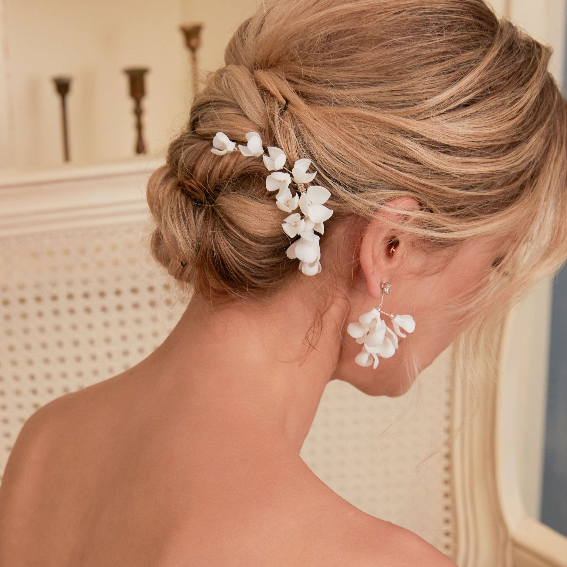 These handcrafted flower bridal earrings are designed to make a statement with their elegant long drop design. Each earring features a cluster of ivory clay blossoms and flowers that gracefully drape from a shimmering rhinestone.