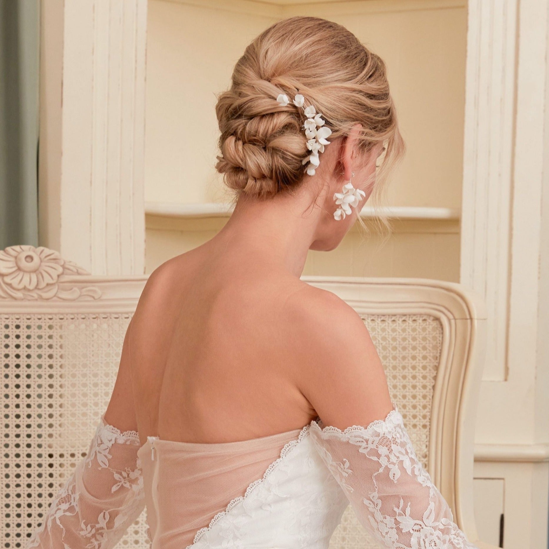 These handcrafted flower bridal earrings are designed to make a statement with their elegant long drop design. Each earring features a cluster of ivory clay blossoms and flowers that gracefully drape from a shimmering rhinestone.