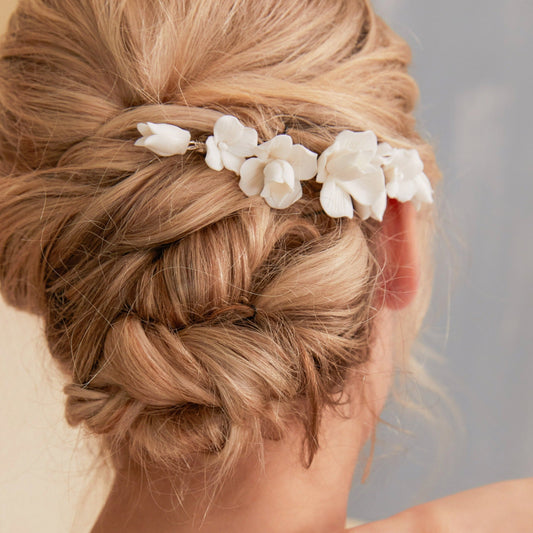 This statement bridal hair clip features carefully handcrafted white porcelain flowers and blossoms, adding an elegant and romantic touch to your hairstyle. It effortlessly enhances any bridal look, creating a timeless style.