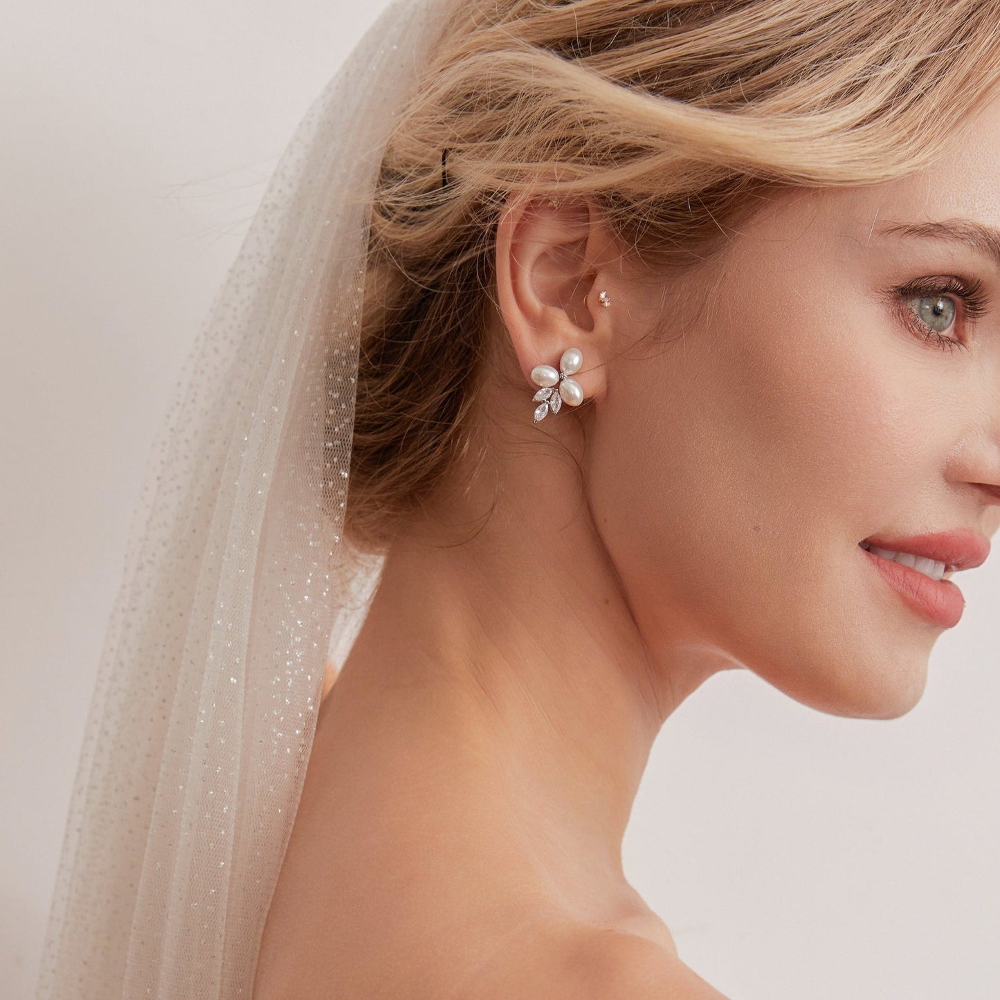 These stunning earrings feature leaf-like zirconia crystals that shimmer beneath three delicate pearls, evoking the graceful beauty of blooming flowers.