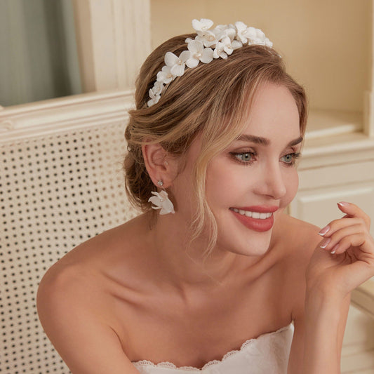 A gloriously romantic hand-sculpted porcelain bridal crown. Made with an arrangement of individually crafted flowers and dainty pearls. This full and textured headband makes a statement but yet still feels incredibly feminine.