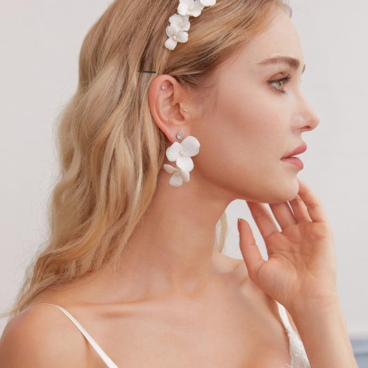Skillfully handcrafted, these flower bridal earrings are the perfect complement to our signature porcelain headpieces. Each earring is exquisitely made by hand, featuring two delicate white clay flowers adorned with freshwater pearls.