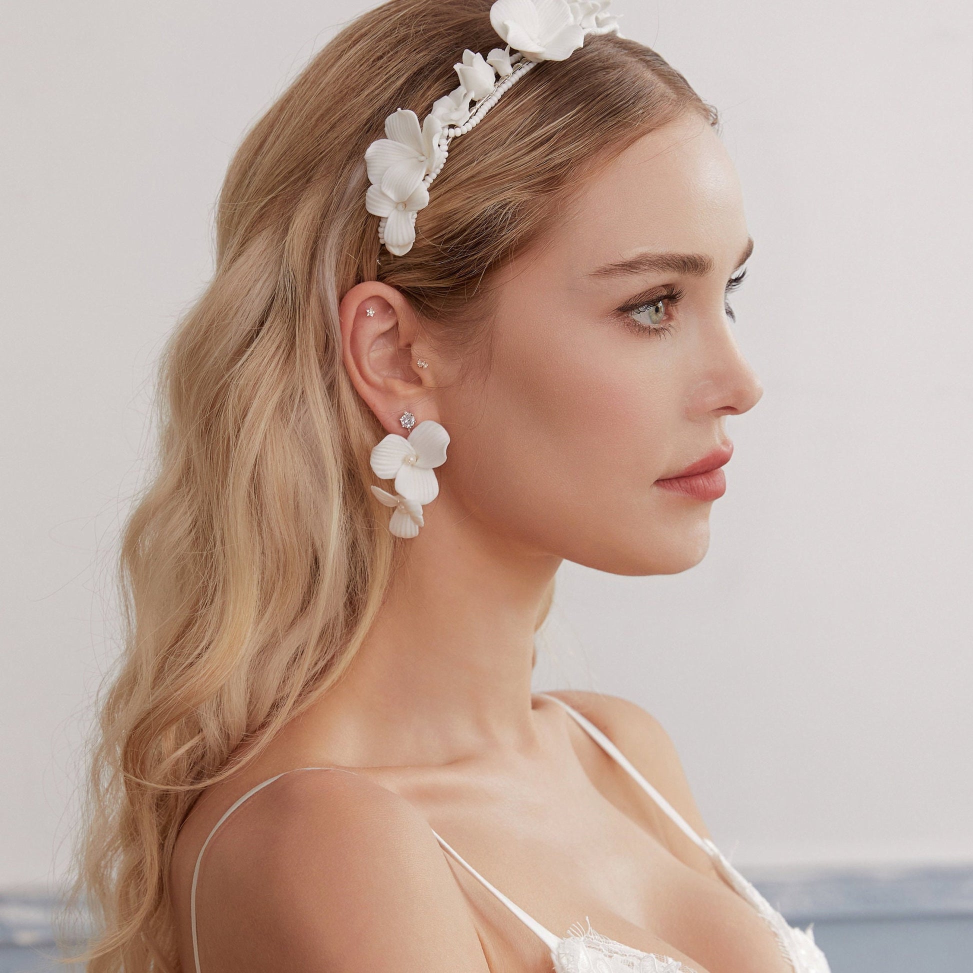 Skillfully handcrafted, these flower bridal earrings are the perfect complement to our signature porcelain headpieces. Each earring is exquisitely made by hand, featuring two delicate white clay flowers adorned with freshwater pearls.