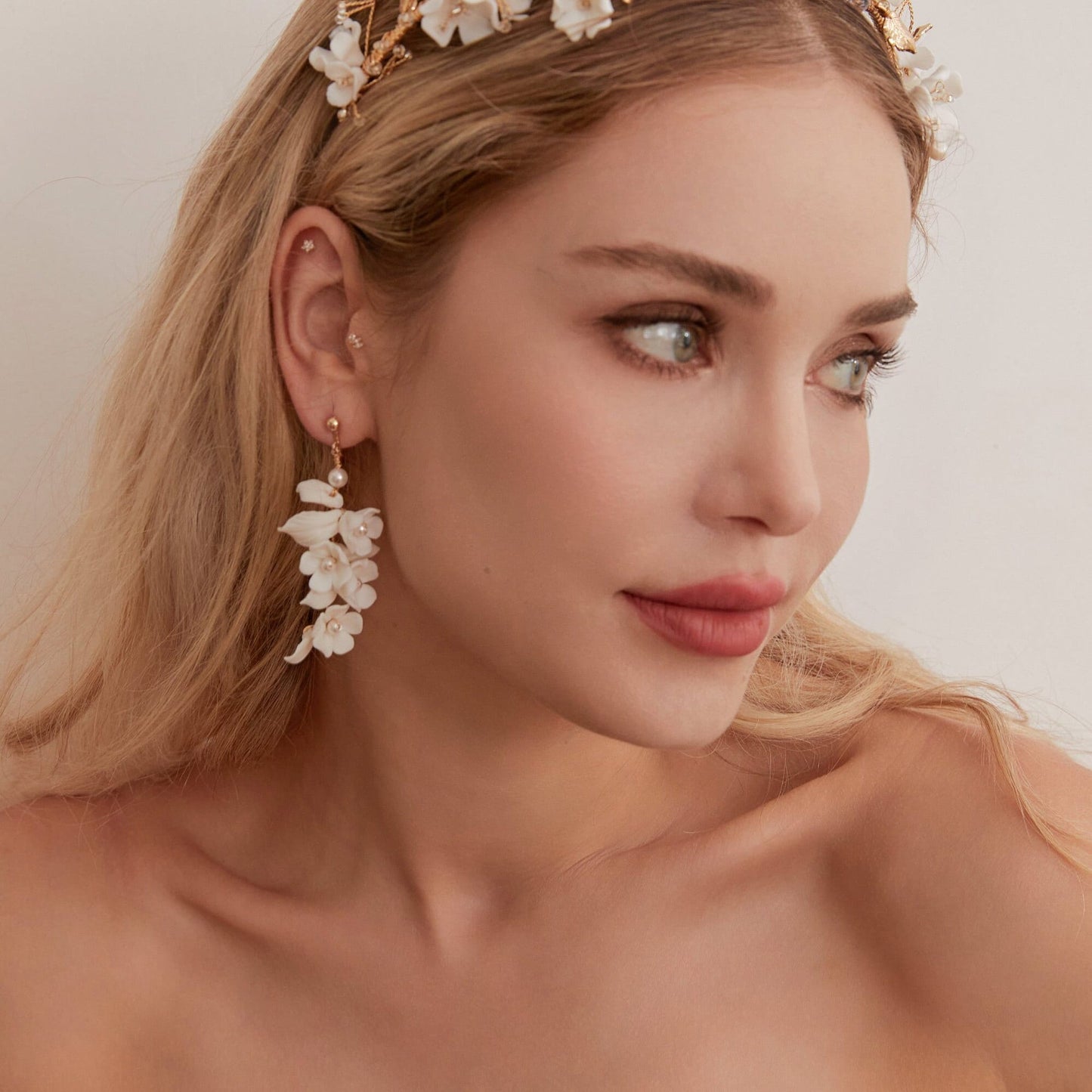 Carefully crafted by hand, these flower bridal earrings are a perfect match to our porcelain headpieces. Each earring features delicate white clay flowers and leaves adorned with shimmering freshwater pearls. These earrings have a long drop design that is sure to catch attention and make a statement.