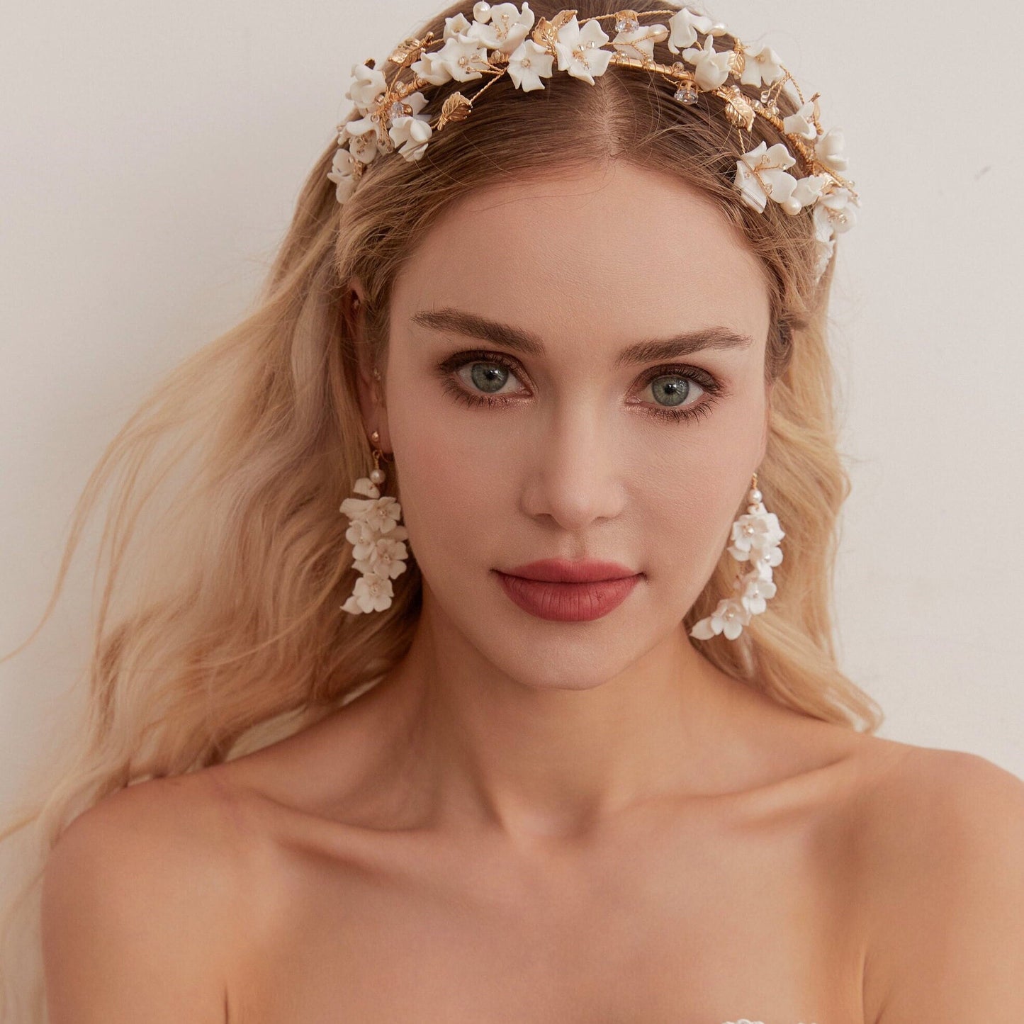 Carefully crafted by hand, these flower bridal earrings are a perfect match to our porcelain headpieces. Each earring features delicate white clay flowers and leaves adorned with shimmering freshwater pearls. These earrings have a long drop design that is sure to catch attention and make a statement.