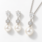 Silver pear-shaped crystal and pearl necklace and earrings set on a pale background