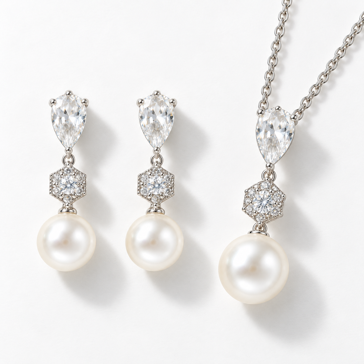 Silver pear-shaped crystal and pearl necklace and earrings set on a pale background
