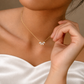 Bride holding her hand beside a delicate gold-coloured flower necklace