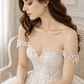 Seated bride wearing a gold leaf bridal hair comb with an off-the-shoulder lace wedding dress