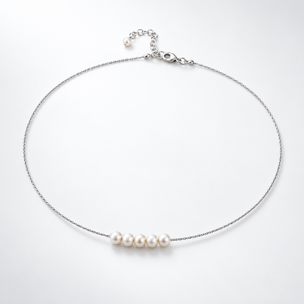 Silver-plated natural pearl necklace laid flat, with five pearls centred on the chain