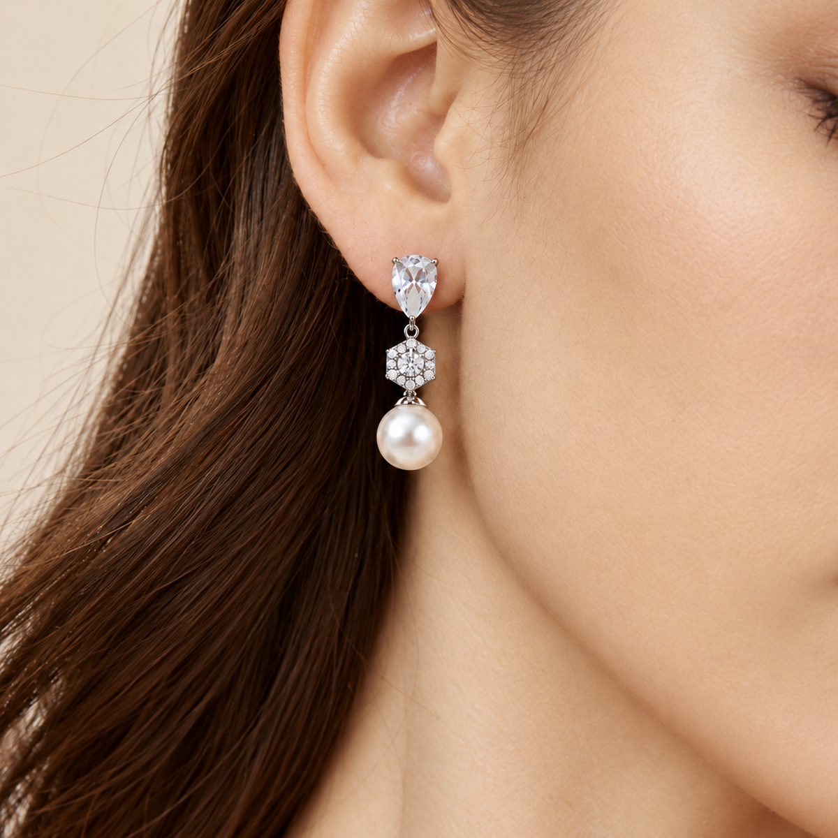 Close-up of a silver crystal and pearl bridal drop earring worn on the ear