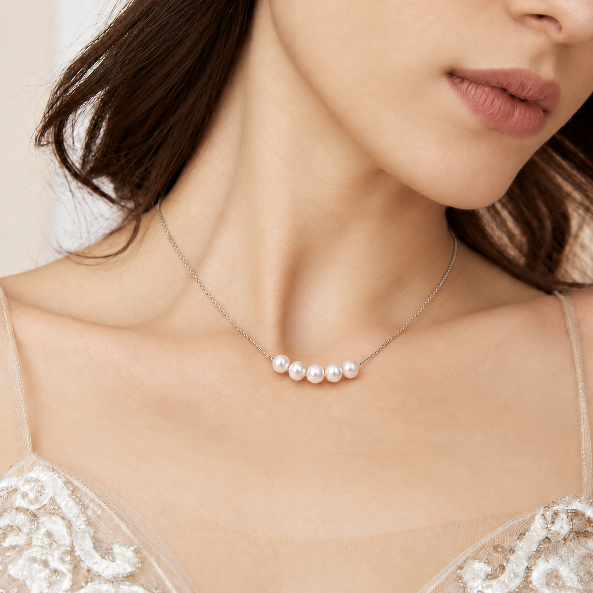 Close-up of a bride wearing a five-pearl silver-plated necklace with a lace wedding dress