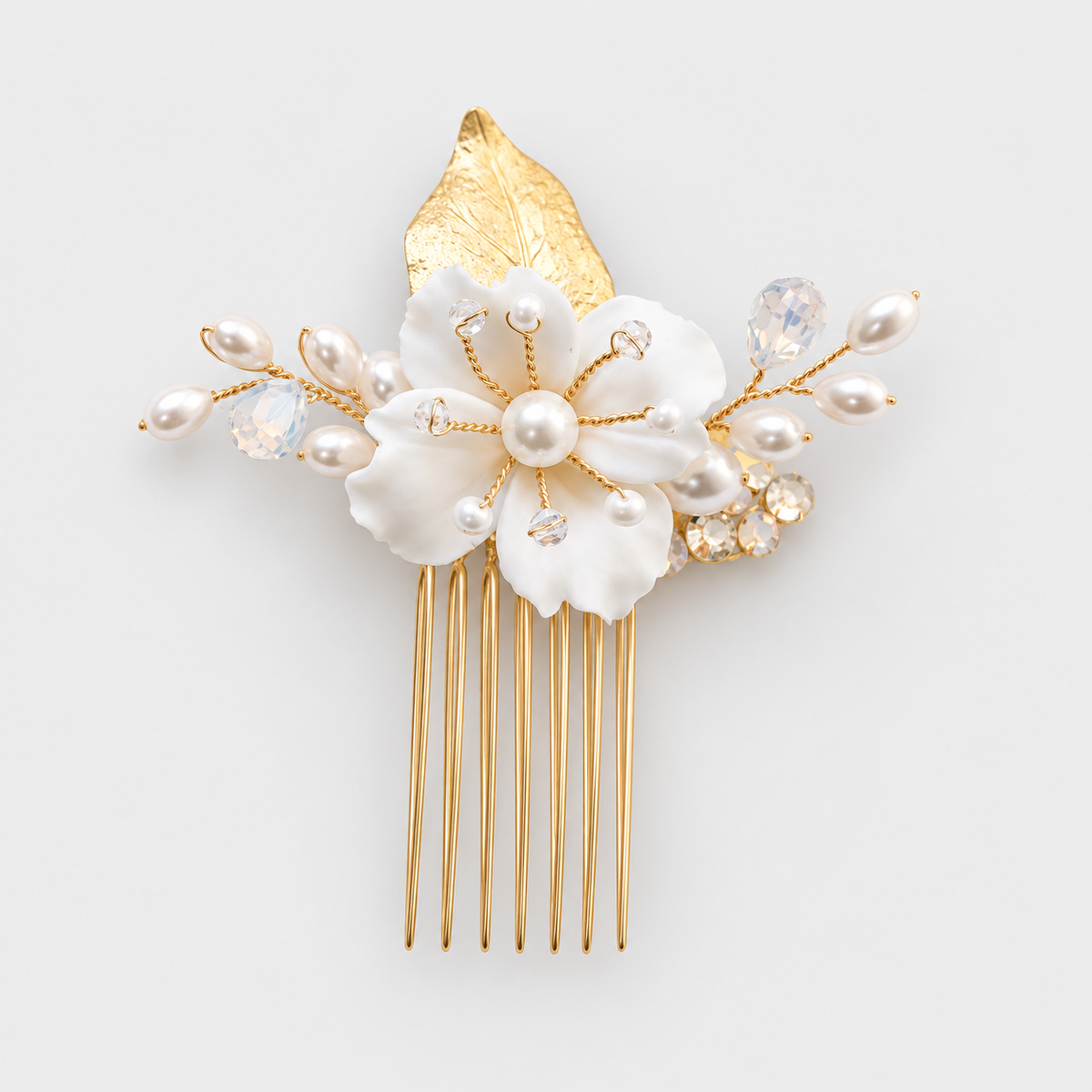 Front view of the white flower and crystal bridal hair comb with gold-tone comb teeth on a pale grey background.