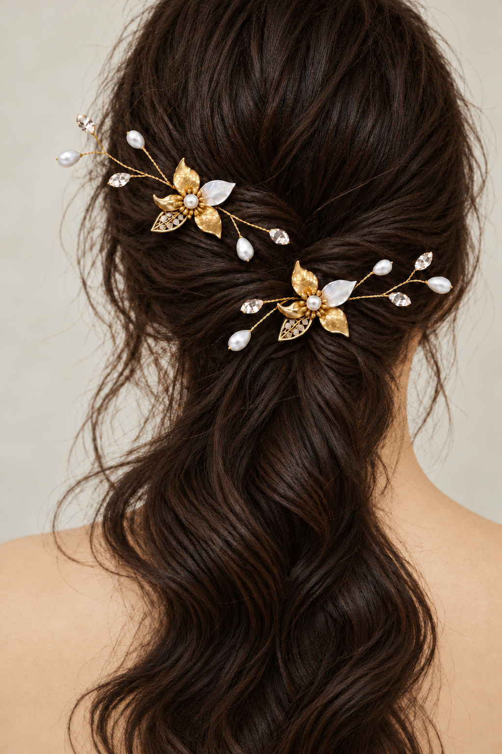 Two gold-plated pearl and CZ leaf bridal hair combs worn in a brown half-up hairstyle, rear view