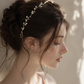 Bride wearing delicate pearl and gold wire wedding crown in side profile, showcasing lightweight adjustable bridal headpiece