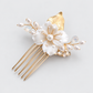 Angled product photo of the white flower and crystal bridal hair comb on a pale grey background.
