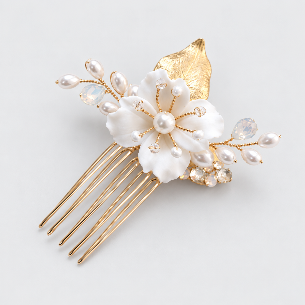 Angled product photo of the white flower and crystal bridal hair comb on a pale grey background.