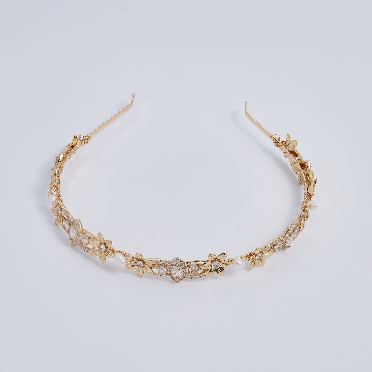 This slimline, modern gold headband is made from the most beautiful freshwater pearls and shimmering rhinestones. The minimalist floral design and timeless luxury of pearls and stones are always in style.