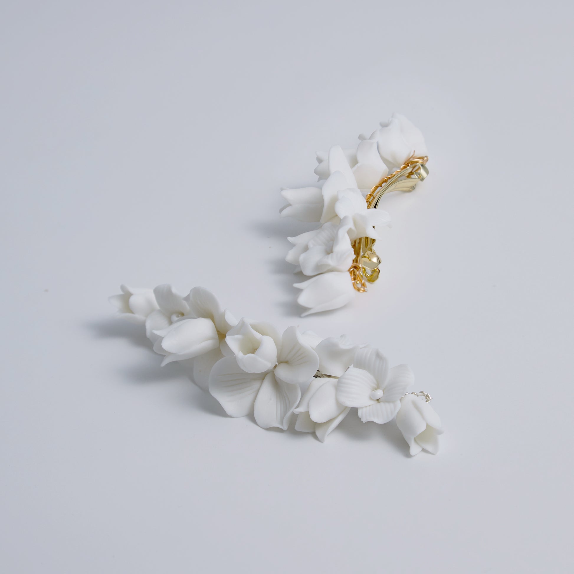 This statement bridal hair clip features carefully handcrafted white porcelain flowers and blossoms, adding an elegant and romantic touch to your hairstyle. It effortlessly enhances any bridal look, creating a timeless style.