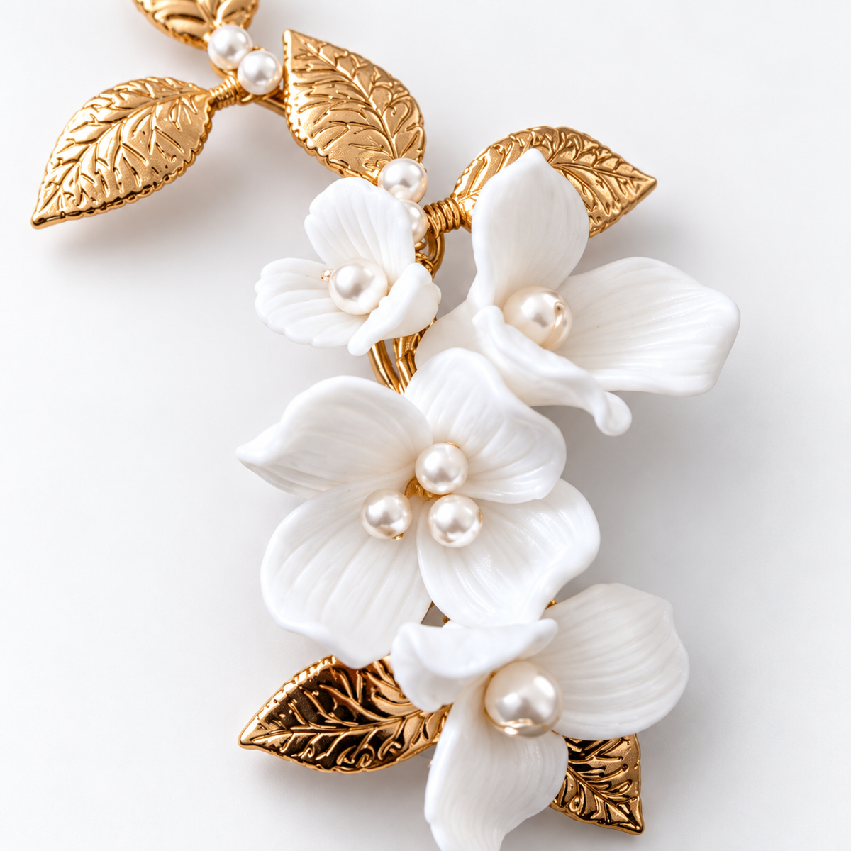 Close-up of sculpted white ceramic petals, pearl-like beads and textured gold leaves