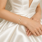 Double-strand pearl bracelet worn with hands crossed over a satin gown