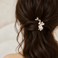 Rear view of a ceramic flower and gold leaf hair clip in a twisted half-up bridal hairstyle