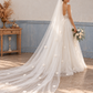 Three-quarter rear view of a bride with a long white floral veil and a bouquet