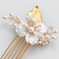 Close-up of the white flower, crystal accents and gold-tone details on the bridal hair comb.