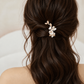 Half-up bridal waves with a white ceramic flower and gold leaf hair clip, rear view