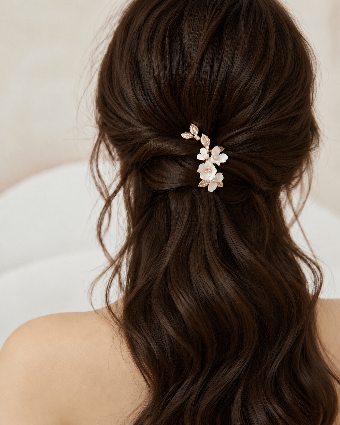 Half-up bridal waves with a white ceramic flower and gold leaf hair clip, rear view