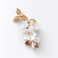 Full view of a single gold and white ceramic flower bridal hair clip on a light grey background