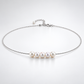 Full view of the silver-plated necklace with five natural pearls on a pale background