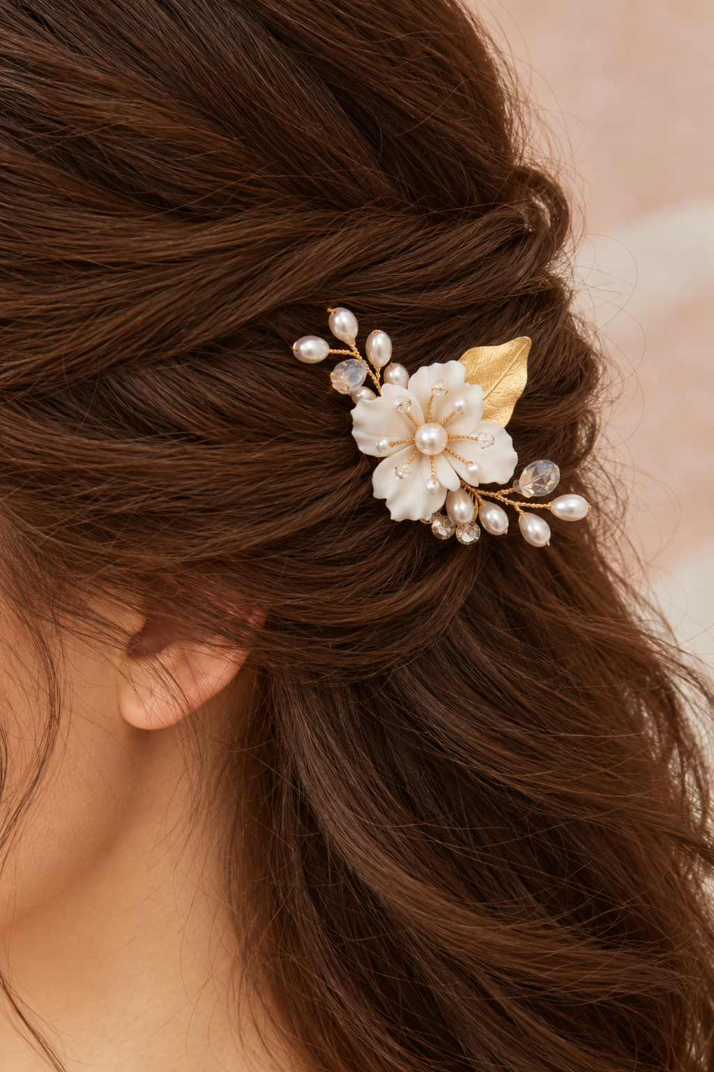 Close-up side view of the white flower and crystal bridal comb worn in brown hair.