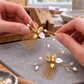 AI-generated craft illustration of hands arranging a gold pearl and CZ hair comb beside its matching comb