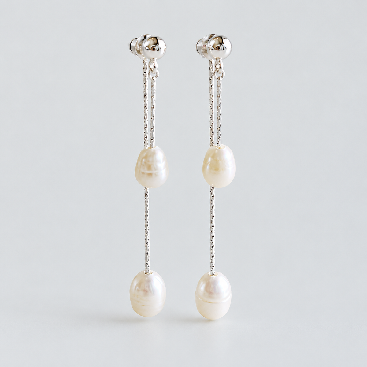 Front view of the pair of freshwater pearl tassel earrings on a pale grey background