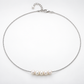 Silver-plated necklace laid in a circle, showing five natural pearls, clasp and extender chain