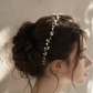Bride wearing delicate pearl and gold wire wedding crown in side profile, showcasing lightweight adjustable bridal headpiece