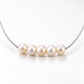 Close-up of five natural pearls arranged along the centre of a silver-plated necklace